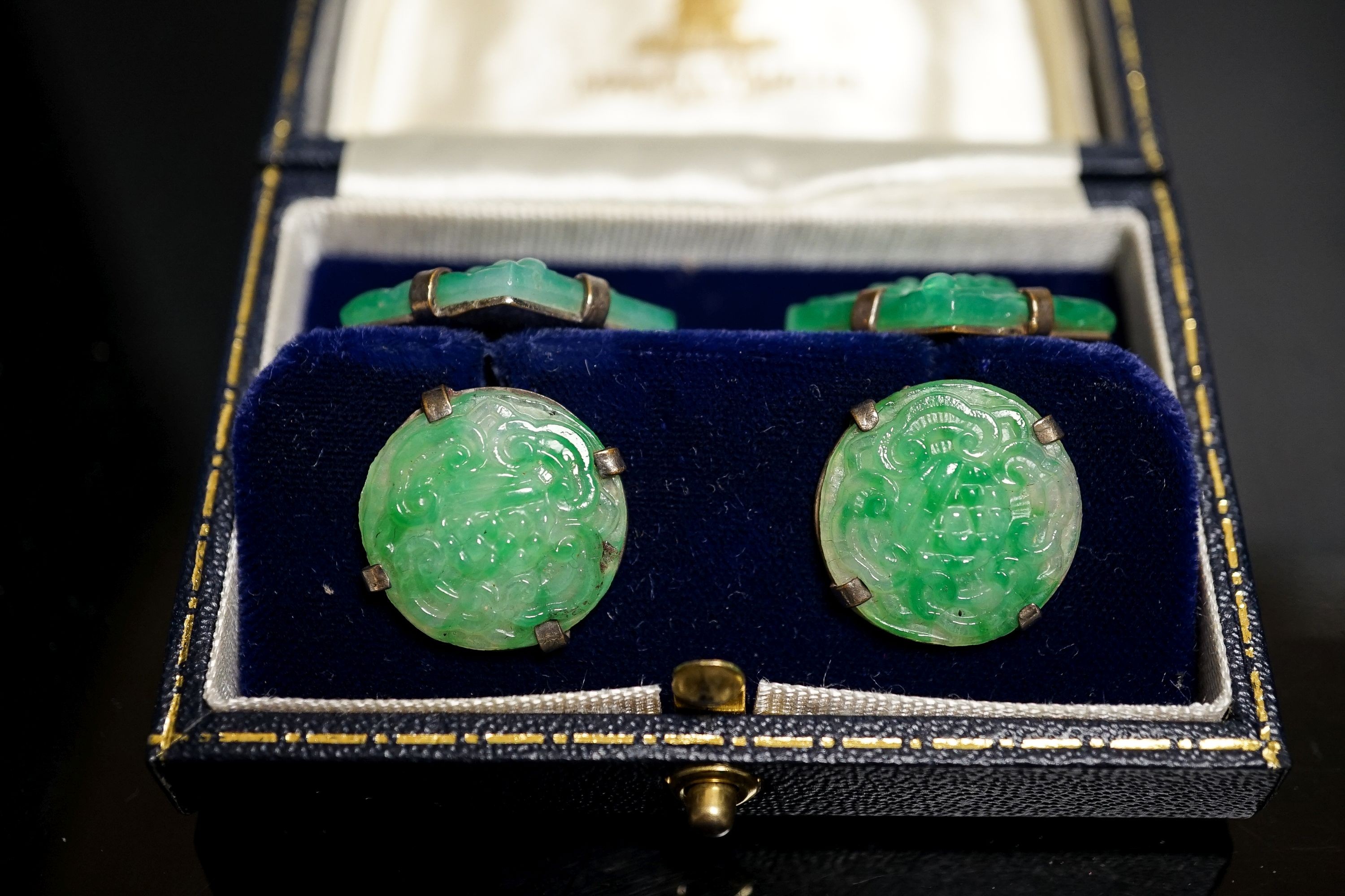 A pair of white metal mounted carved jade cufflinks, largest panel approx. 25mm.